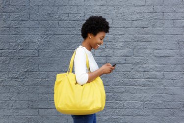 Happy young woman reading text message on mobile phone