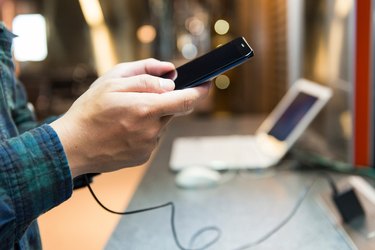 Cropped Hands Of Man Using Phone At Table